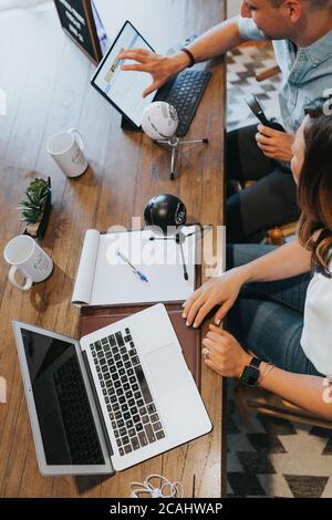 Arbeiten von zu Hause aus allein und gemeinsam auf Laptops, Schreiben von Notizen und Hören und Aufnehmen von Podcasts. Stockfoto