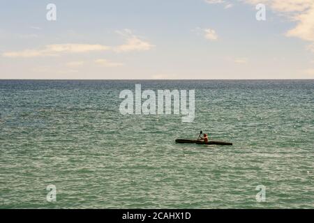 Seascape mit einem Mann Kanufahren und klaren blauen Himmel im Sommer, Recco, Genua, Ligurien, Italien Stockfoto