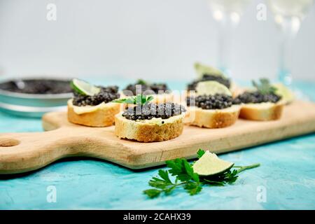 Stör schwarzer Kaviar in Holzschale, Sandwiches und Champagner auf weißem Hintergrund Kopierraum. Stockfoto