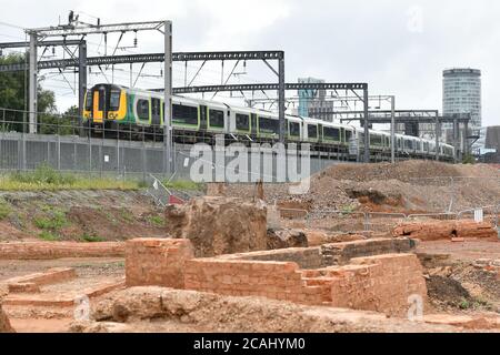 Ein Zug fährt an einem Damm über der Baustelle für den HS2 Rail Link Staion in der Curzon Street in Birmingham, England, UK vorbei Stockfoto