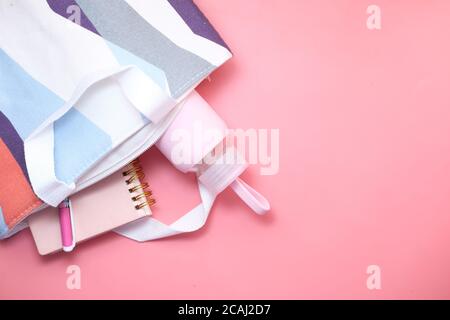 Saitenbeutel mit wiederverwendbarer Wasserflasche und Notizblock auf rosa. Stockfoto