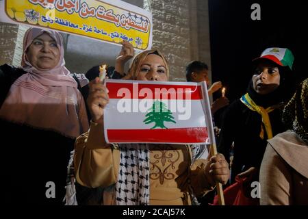 Gaza, Palästina. August 2020. Eine Palästinenserin hält eine libanesische Flagge und eine brennende Kerze während eines solidaritätsmarsches mit den Libanesen nach einer gewaltigen Explosion im Hafen von Beirut. Kredit: SOPA Images Limited/Alamy Live Nachrichten Stockfoto