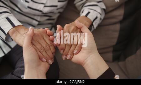 Nahaufnahme, junge Frau und ältere Frau halten die Hände. Familienbindekonzept. Hochwertige 4k-Aufnahmen Stockfoto