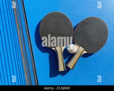 Set aus zwei Tischtennisschlägern und einem Ball auf Eine Tischtennisplatte mit einem Netz Stockfoto