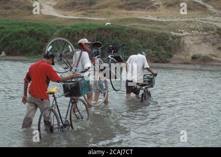 Gruppe Mexikaner mit Fahrrädern, die über einen flachen Fleck im Rio Grande River, der Grenze zwischen den Vereinigten Staaten und Mexiko, in der Nähe von Brownsville, Texas, waten. ©Bob Daemmrich Stockfoto