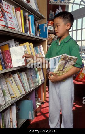 Austin Texas USA, 1991:Vietnamesisch-amerikanischer Junge der Klasse 5th schaut sich Bücher in der Kinderabteilung in einer örtlichen Buchhandlung an. HERR EV-005 ©Bob Daemmrich Stockfoto