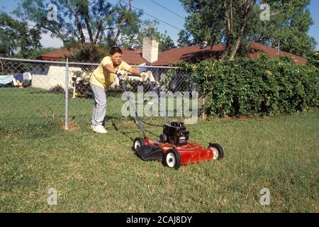 Austin, Texas USA,1988: Hispanischer Junge, 13, Rasenmähen mit gasbetriebenem Mäher. MR RR-0092. ©Bob Daemmrich Stockfoto