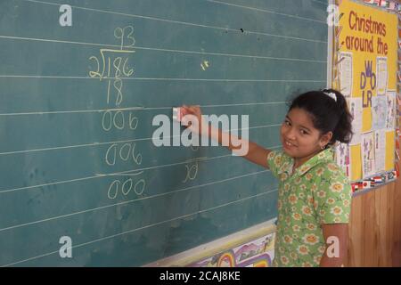 Hispanische Mädchen der 5. Klasse erklärt ihr Problem mit der langen Teilung auf der Tafel in der Klasse. Modellversion. ©Bob Daemmrich Stockfoto