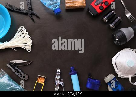 Flache Ansicht der wichtigsten Gegenstände für die Katastrophenvorsorge, die ordentlich für eine Handtasche angeordnet sind, einschließlich Notfallvorräte, erste-Hilfe-Materialien Stockfoto