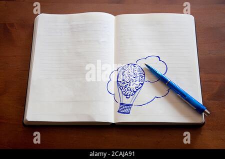 Doodle hot-air balloon paper Notebook Pen wooden background Stockfoto