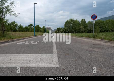 'Stop' geschrieben auf Asphaltstraße mit blauem Himmel, Wolken, Berge und Häuser im Hintergrund Stockfoto