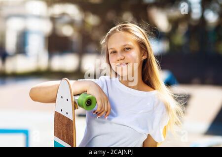 Mädchen Teenager posiert mit einem Skateboard in ihren Händen in Der Park an einem sonnigen Sommertag Stockfoto
