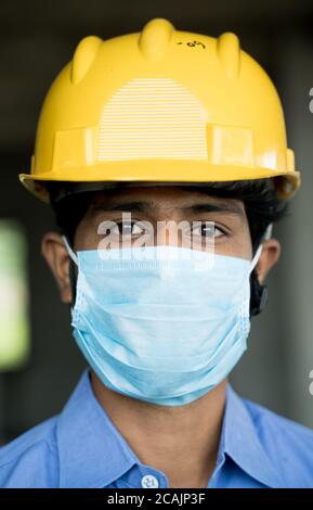 Kopf Schuss von Bauarbeiter, Wiedereröffnung von Baustellen oder Industrie - Bauarbeiter in einem Bauhelm mit medizinischer Maske aufgrund Stockfoto