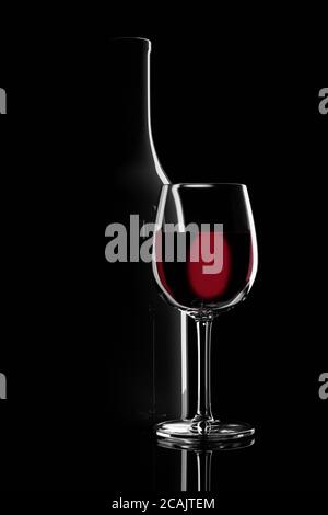 Ein Glas Rotwein neben einer Flasche mit Hintergrundbeleuchtung auf schwarzem Hintergrund. 3d-Illustration. Stockfoto