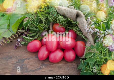 Lange Pflaume mit Basilikum auf Holztisch. Haufen frischer Tomaten in Sackleinen auf Holztisch. Natürliches Produktkonzept. Stockfoto