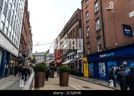 Dublin, Irland - 30. Dezember 2019: Einkaufsstraße mit Restaurants, Geschäften, Menschen und Weihnachtsdekoration im Zentrum von Dublin, Irland Stockfoto