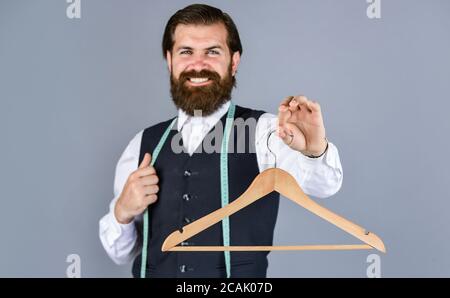 Für Sie. Schneider Mann verwenden Maßband. Professionelle männliche sartor mit Maßband und Aufhänger. Handsome Mann in Smart Casual Wear hält Kleiderbügel. Portrait des Mannes hält Kleiderbügel. Stockfoto