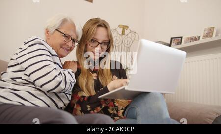 Oma und Enkelin beobachten alte Fotos auf dem Tablet. Niedriger Winkel. Hochwertige Fotos Stockfoto