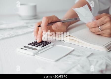 Die Person zählt die bezahlten Rechnungen auf dem Rechner. Hausbuchhaltung. Stockfoto