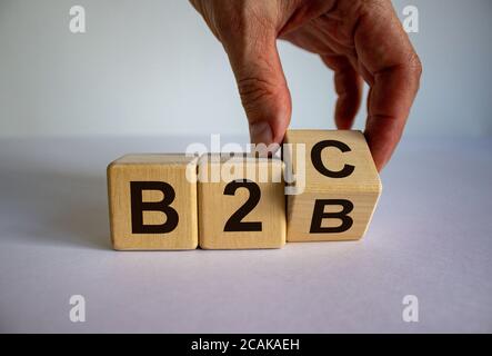 Business to Business oder Business to Consumer. Hand dreht einen Würfel und ändert den Ausdruck 'B2C' in 'B2B' oder umgekehrt. Geschäftskonzept. Wunderschön Stockfoto