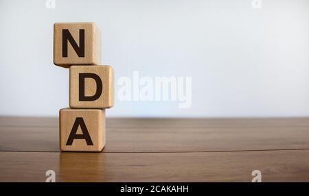 Konzeptwort "NDA" auf Kuben auf einem schönen Holztisch. Weißer Hintergrund. Geschäftskonzept. Speicherplatz kopieren. Stockfoto