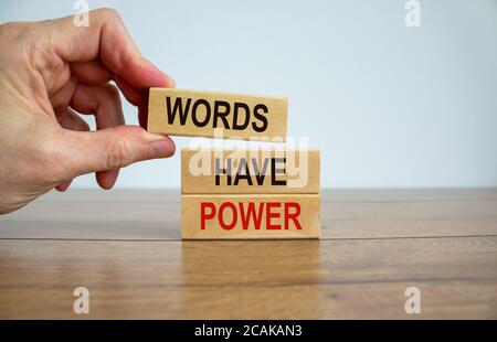Männliche Hand, die einen Block mit dem Wort „Wörter“ auf einem Block-Turm mit den Worten „Macht haben“ platziert. Holztisch. Schöner weißer Hintergrund. Speicherplatz kopieren. Bu Stockfoto