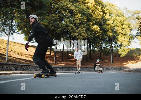 Die Jungs führen Tricks und reiten. Auf einem Skateboard in der abends warmen Stadt. Stockfoto