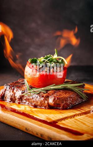 Gegrilltes Fleisch mit Gemüse auf Feuer auf einem Holzbrett. Stockfoto