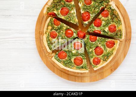 Hausgemachter Spinat Quiche auf einem runden Bambusbrett, Draufsicht. Flachlage, über Kopf, von oben. Leerzeichen für Text. Stockfoto