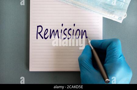 Männliche Ärzte Hand in blauen Handschuh schreibt die Worte "Mission" auf eine weiße Note. Arznei Maske. Schöner blauer Hintergrund. Stockfoto