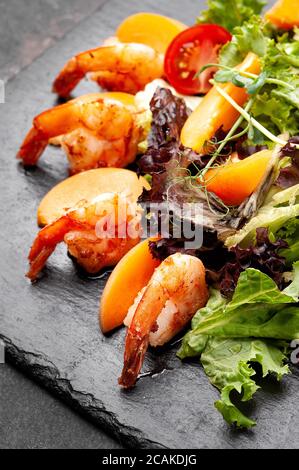 Frischer Salat mit Garnelen auf schwarzem Teller. Stockfoto