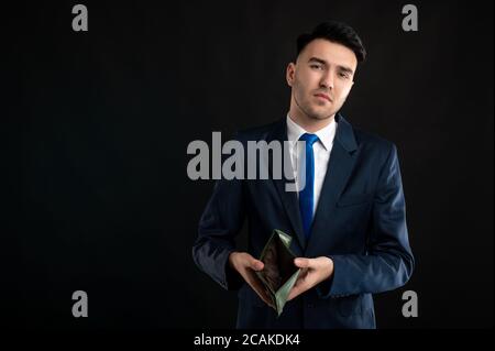 Porträt eines Geschäftsmanns mit blauem Business-Anzug und Krawatte Leere Brieftasche wird auf schwarzem Hintergrund mit Kopierplatz isoliert angezeigt Werbebereich Stockfoto