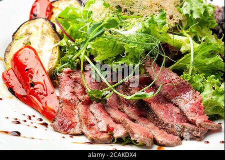 Gegrilltes Gemüse mit Fleisch und frischem Salat auf einem weißen Teller. Stockfoto