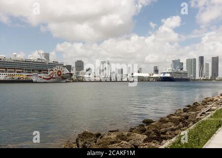 Ein norwegisches Kreuzfahrtschiff und ein Celebrity Cruises-Schiff, die in PortMiami, der Cruise Capital of the World, mit der Skyline im Hintergrund, in Miami, Florida, USA, festgemacht sind Stockfoto