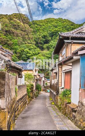 chiba, japan - juli 18 2020: Schmaler Pfad zwischen mit Moos bedeckten Steinmauern im Fischerdorf Kanaya in der Stadt Futtsu am Fuße des Berges No Stockfoto