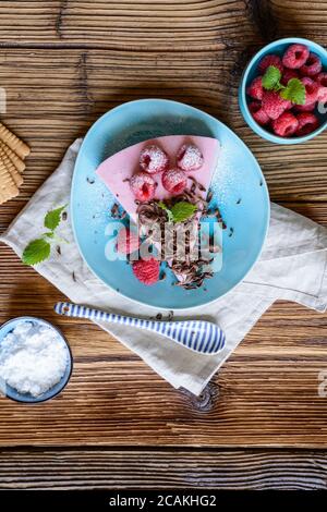 Erfrischender, nicht gebackener Himbeer-Käsekuchen mit frischen Beeren, serviert auf einer Keramikplatte Stockfoto