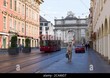 Innsbruck / Österreich - September 2019: Ein Mann läuft entlang der Straßenbahnlinien in der Nähe des Triumphbogens im Zentrum von Innsbruck nach Hause Stockfoto