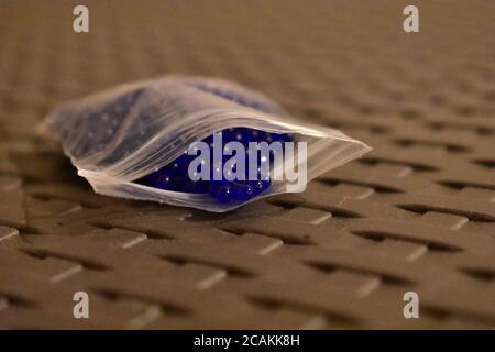 Winzige blaue Kugeln in einer Plastiktüte auf einem Gitter Tabelle Stockfoto
