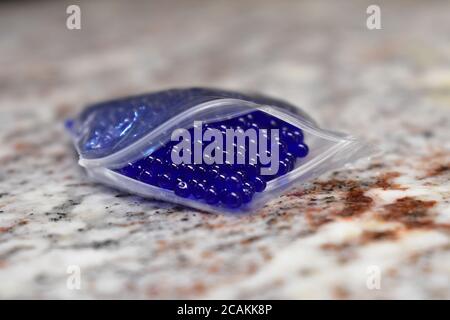 Winzige blaue Kugeln in einer Plastiktüte auf einem Granit Arbeitsplatte Stockfoto