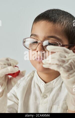 Nahaufnahme Porträt von gemischten Rennen Kind in Brille und Handschuhe experimentieren mit Schleim Stockfoto