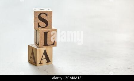 Stapel mit drei Holzwürfeln - Buchstaben SLA Bedeutung Service Level Agreement auf ihnen, Platz für mehr Text / Bilder auf der rechten Seite. Stockfoto