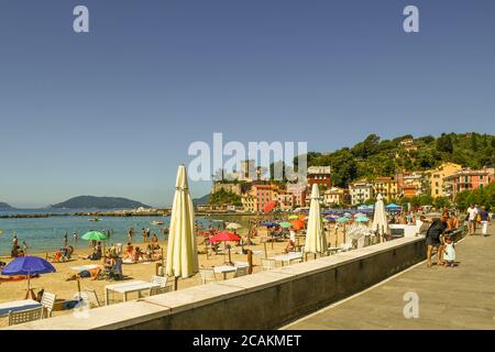 Blick auf das alte Fischerdorf am Ufer des Golfs der Dichter mit Menschen am Strand im Sommer, San Terenzo, La Spezia, Ligurien, Italien Stockfoto