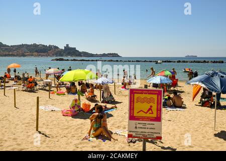 Blick auf den öffentlichen Strand überfüllt mit Urlaubern mit dem Vorgebirge von Lerici am Horizont im Sommer, San Terenzo, La Spezia, Ligurien Italien Stockfoto