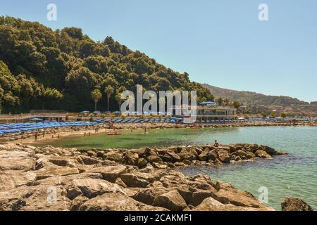 Panoramablick auf den Strand von San Terenzo von der felsigen Küste mit dem bewaldeten Park der Villa Marigola auf dem Hügel im Sommer, La Spezia, Ligurien, Italien Stockfoto