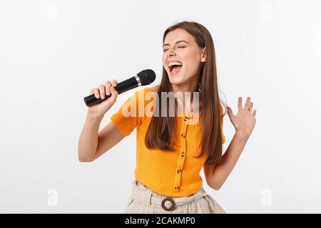 Junge hübsche Frau glücklich und motiviert, singen ein Lied mit einem Mikrofon, ein Ereignis oder eine Party, genießen Sie den Moment Stockfoto