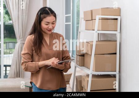 Glückliche junge asiatische Unternehmer mit Tabletten für Check-Bestellung und Überprüfung Lager für die Lieferung von Produkten an Kunden. Inhaber und Erfolg von Kleinunternehmen Stockfoto