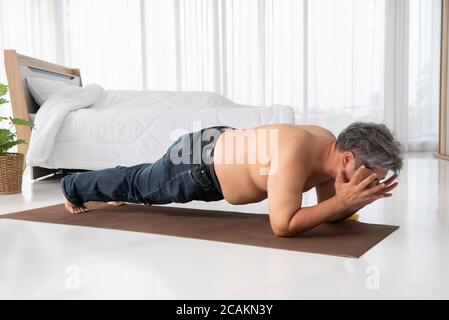 Fat asiatische Männer versuchen, Planken mit Entschlossenheit zu machen und versuchen hart, Gewicht zu verlieren. Beim Betreten vor dem Ausgehen zur Arbeit. Konzept des Workouts Stockfoto