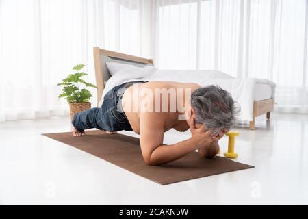 Fat asiatische Männer versuchen, Planken mit Entschlossenheit zu machen und versuchen hart, Gewicht zu verlieren. Beim Betreten vor dem Ausgehen zur Arbeit. Konzept des Workouts Stockfoto