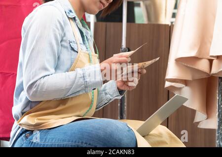 Gestresste asiatische Unternehmerin sitzt neben dem Fenster, weil ihr Geschäft aufgehört hat, Geschäfte zu machen. Aufgrund finanzieller Probleme und der Konjunkturabschwächung Stockfoto