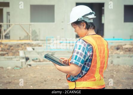 Asiatische Frauen Arbeiter und Techniker über die Verwendung von Tablet für die Überprüfung der Genauigkeit in den Plätzen vor dem Gebäude und Häuser. Stockfoto